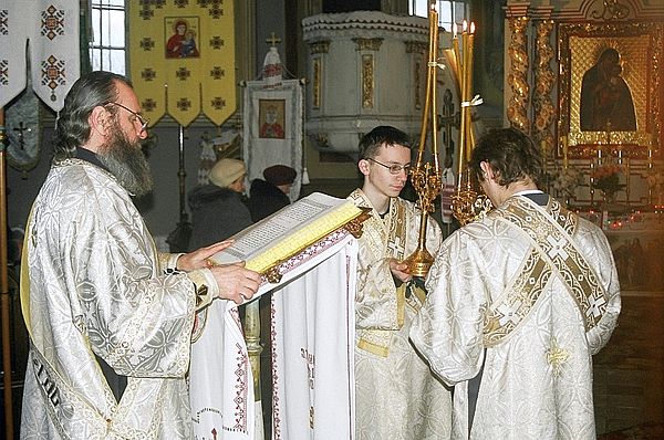 Subdeacons holding the episcopal candles while deacon reads the Gospel