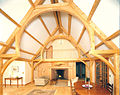 A bent in a finished timber frame home in the form of a hammerbeam truss.