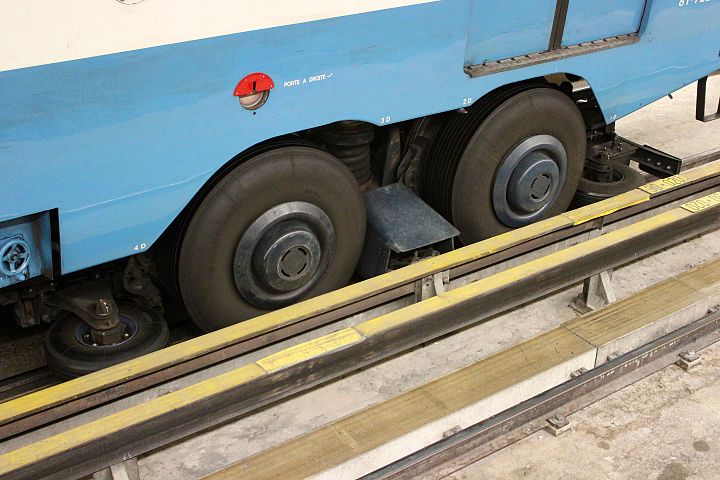A rubber-tyred metro bogie. Between the two large tires a contact shoe touches the guidebar and electrically grounds the car