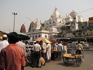 Extremidade oriental da Chandni Chowk. O edifício branco é o Gauri Shankar Mandir, um emplo hindu dedicado a Xiva. À esquerda avistam-se as torres vermelhas do Digambara Mandir, o templo jainista mais antigo de Deli.