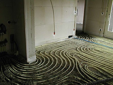 In underfloor heating, tubing is placed on the floor throughout the room and later covered with a concrete layer during construction.