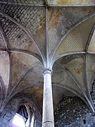 Photographie en couleurs d'une colonne surmontée de voûtes en palmier.