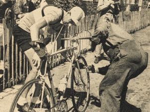 Photo en noir et blanc d'un cycliste professionnel debout en train d'inspecter son vélo.