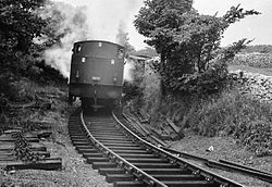 A railtour rounds the curve carrying enthusiasts in brake vans and open wagons in 1964. Gotham curve.jpg