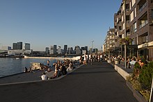 Foto einer Hafenpromenade mit vielen Fußgängern und Sitzgelegenheiten entlang des Ufers