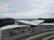 Front view of the TWA Hotel from a nearby parking lot; the AirTrain JFK track is in the foreground JFK T5 May 2019 06.jpg