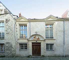 Foto van een gevel van een oud huis, laag, in tufsteen.