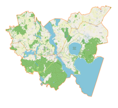 Mapa konturowa gminy Mikołajki, blisko centrum na dole znajduje się owalna plamka nieco zaostrzona i wystająca na lewo w swoim dolnym rogu z opisem „Jezioro Mikołajskie”