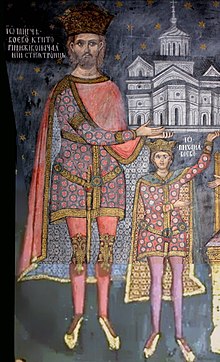 A bearded man and a boy (both wearing a crown) hold a church on their hands