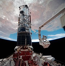 Musgrave being raised to the top of Hubble by Canadarm, as it sits in Endeavour's payload bay. STS061-98-050 - Astronauts Musgrave and Hoffman during servicing of HST (Retouched).jpg