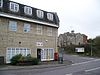 Stone 3-storey building with white frames windows on street junction. Sign saying shop.