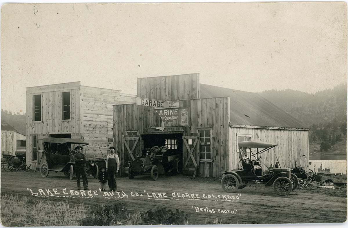 https://upload.wikimedia.org/wikipedia/commons/thumb/4/45/Two_men_and_a_child_in_front_of_an_auto_shop%2C_Lake_George%2C_c._1914_-_DPLA_-_4a82b3f10372c0eaa7d403e14af58665.jpg/1200px-Two_men_and_a_child_in_front_of_an_auto_shop%2C_Lake_George%2C_c._1914_-_DPLA_-_4a82b3f10372c0eaa7d403e14af58665.jpg