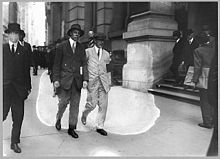 Upton Sinclair wearing a white suit and black armband, picketing the Rockefeller Building in New York City