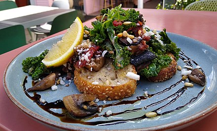 A kale-based dish with other vegetables and sourdough bread, served at a restaurant in Australia