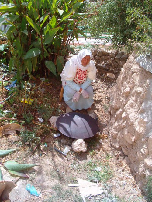 A Palestinian woman baking markook bread on tava or Saj oven in Artas, Bethlehem, Palestine