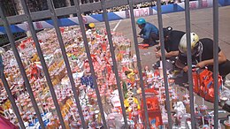 Drinks and canned yellow peaches were laid at the school gate, with flowers of condolence visible afar. Min Zhong Fen Fen Gei Hai Zi De Huang Tao Guan Tou He Nai Cha .jpg