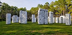 Photograph of Bamahenge showing pillars erected in a grassy area and trees in the background