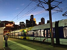 Yellow light rail downtown at night, Minneapolis skyline behind