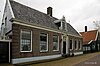 Koopmanshuis D'Mol. Grotendeels houten huis in L-vorm. Brede bakstenen voorgevel met geblokte hoeklisenen en in het midden een rijk versierde ingangspartij met Ionische pilasters.