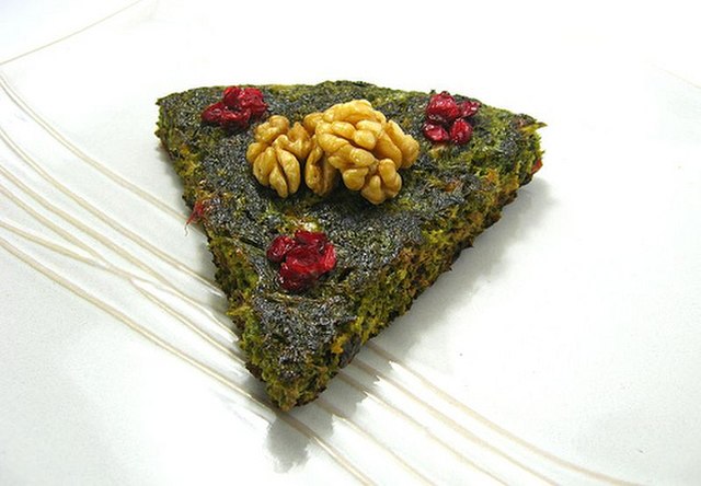 Kuku sabzi (herb kuku) topped with barberries and walnuts