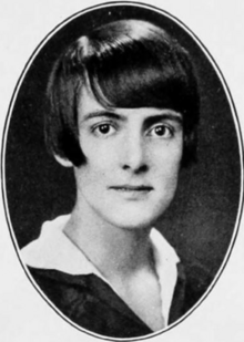 A young white woman with dark hair cut in a bob with a sidepart and bangs, in an oval frame