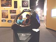 Nina, Jaydon and Ana Lisa, posing behind the Tucson Meteorite on exhibit in the “Origins Hall”