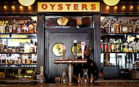 The high shelves behind the bartender at New Orleans' Superior bar display the establishment's expensive, "top shelf" liquor brands. Our bartender at Superior, New Orleans 2016.jpg