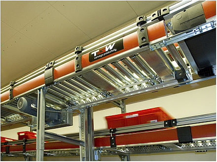 Belt driven roller conveyor for cartons and totes.