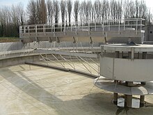 Drained circular sedimentation tank showing central inlet baffles on the right with solids scraper and skimmer arms visible under the rotating bridge. Sedimentation tank.jpg