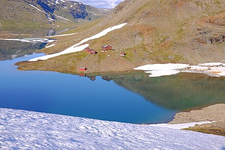 The Sorjushytta cabins in the Sulitjelma mountains seen across the lake, mid August after a cold spring