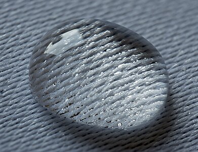 Water droplet laying on a damask textile due to surface tension and low absorbtion of textile. Focus stacking: 24 shots, step 5; Raynox 250