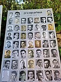 שלט ההנצחה עם שמות ותמונות של 52 לוחמים שנפלו בקרב בטקס באזכרה