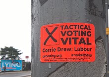 A sticker in Bournemouth calling for tactical voting with an anti-Conservative billboard in the background 2019 election in Bournemouth.jpg