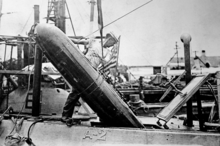 A crewman guiding one of the submarine's three torpedoes below deck through the torpedo loading hatch. A-2 torpedo loading.png