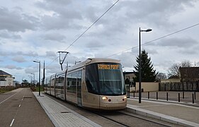 Kolorowe zdjęcie tramwaju widzianego nieco z profilu, z opuszczonymi peronami po obu stronach.