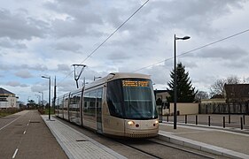 Photographie en couleurs d'un tramway vu légèrement de profil, les quais de part et d'autre étant déserts.