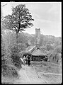 Paysan avec sa carriole devant le calvaire et l'église de Saint-Herbot au début du XXe siècle.