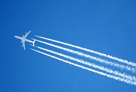 高空を飛行するジェット機のエンジンが凝縮した跡 (飛行機雲) を残す