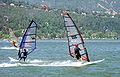 Windsurfers op de rivier met een beboste heuvel op de achtergrond