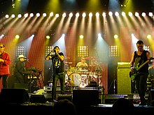 Break My Heart interpolates the rhythm-guitar melody from Need You Tonight by INXS (pictured).[118]