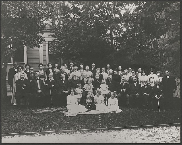 Charles Nibley, second from the left of the seated row of men, in front of the house of J.G. McDonald in 1911