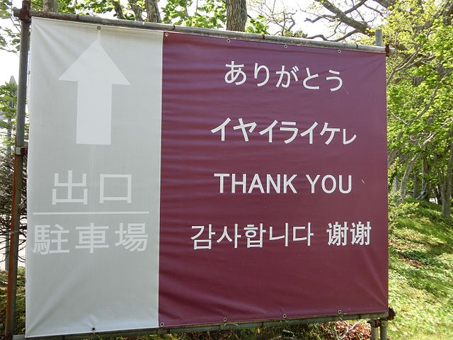 Multilingual sign in Japanese, Ainu, English, Korean, and Chinese. The Ainu text, in katakana, is second down from the top on the right side of the si