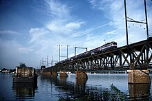 Batu jembatan dermaga di sungai yang luas, di samping jembatan rangka baja