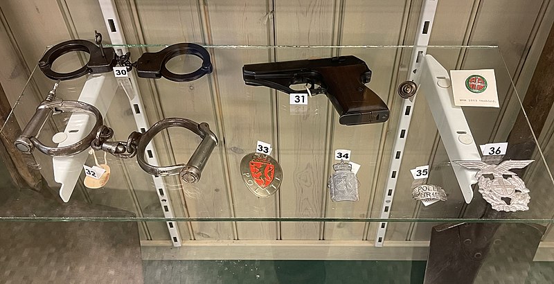 File:Politiet under krigen Norwegian WW2 Police 30 32 Håndjern hand cufffs 31 Mauser HSc pistol 33-35 Politiskilt 36 Statspoliti luemerke NS-skarven Unghird Hjemmefrontmuseet Rakkestad local museum Norway IMG 5799.jpg