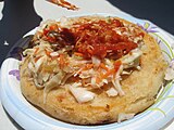 Un pupusa avec de la sauce tomate et du curtido.