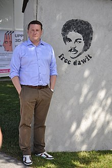 Tobias Baudin berdiri di samping mural yang menggambarkan Dawit Isaak dengan "gratis dawit" tertulis di bawah ini