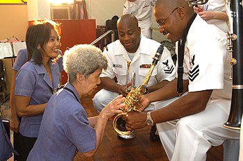 Members of the Seventh Fleet Band engaging in cultural diplomacy at the Pattaya Redemptorist School for the Blind US Navy 060227-N-1194D-009 Seventh Fleet band member Musician 1st Class Frank Newton demonstrates how his saxophone keys operate to Aurora Sribuapun, headmaster of the Pattaya Redemptorist School for the Blind.jpg