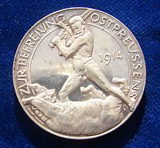 The reverse of a World War I German Silver medallion liberation of East Prussia 1914 by Paul von Beneckendorff und von Hindenburg. Referring to the Battle of Tannenberg. The naked General Hindenburg fighting the Russian Bear with his sword.