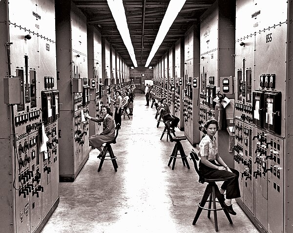 Employees of the Manhattan Project operating calutron control panels at Y-12, in a US government photo by Ed Westcott.