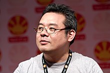 A black haired Japanese man wearing glasses.